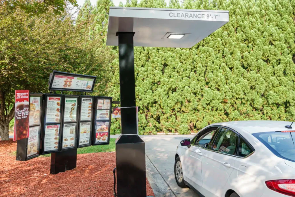 A modern fast-food drive-thru with digital menu boards and a clearance bar, illustrating the setting where voice AI ordering automation can be implemented smartbrief