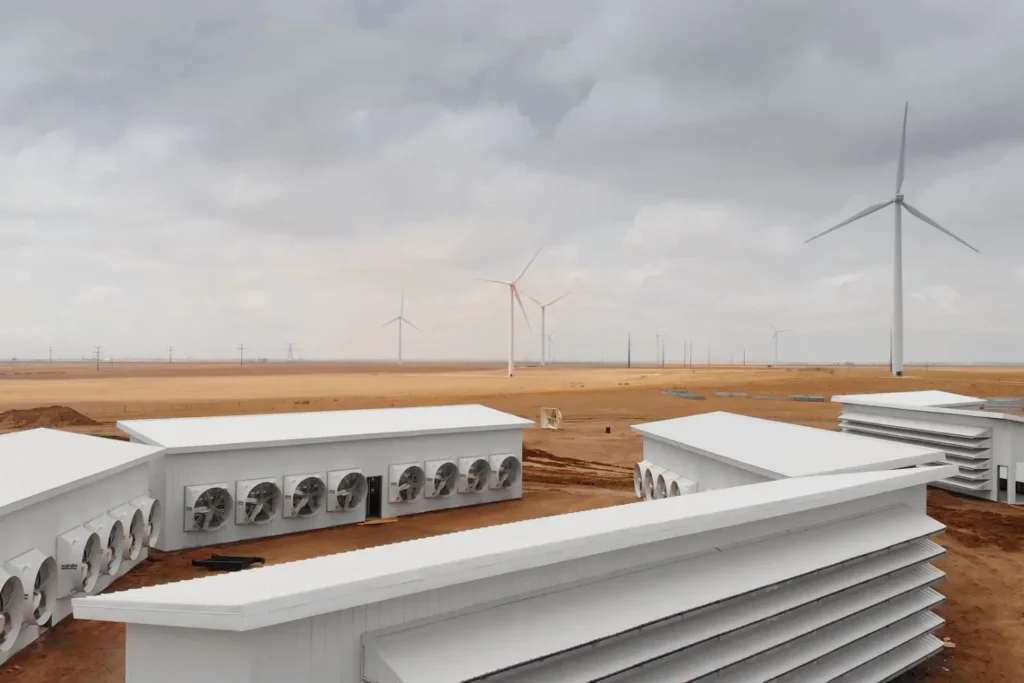 A Bitcoin mining farm powered by wind energy with cooling infrastructure and multiple wind turbines in a desert setting 