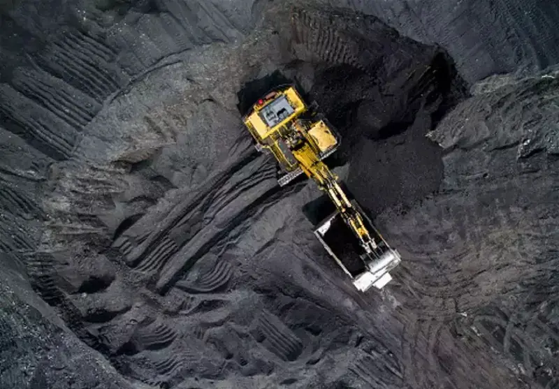 Aerial view of a large yellow excavator at an open-pit mining site, illustrating Vedanta's mining operations 