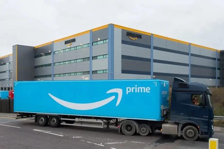 Prime delivery truck at a large Amazon warehouse, illustrating the company's extensive logistics network