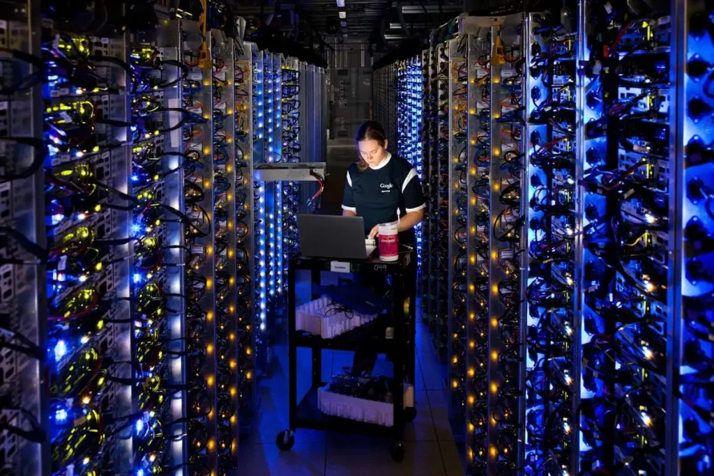 A technician monitoring GPU-powered server racks inside a modern AI data center illuminated with blue and yellow lights