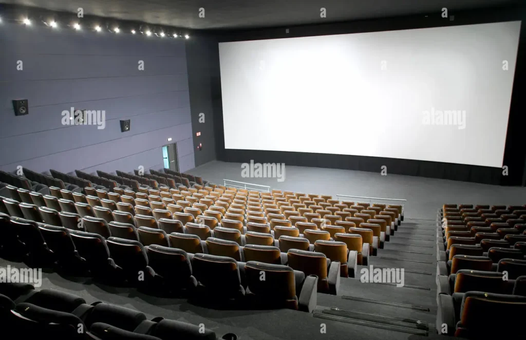 Modern multiplex cinema hall interior with tiered seating and a large blank screen 