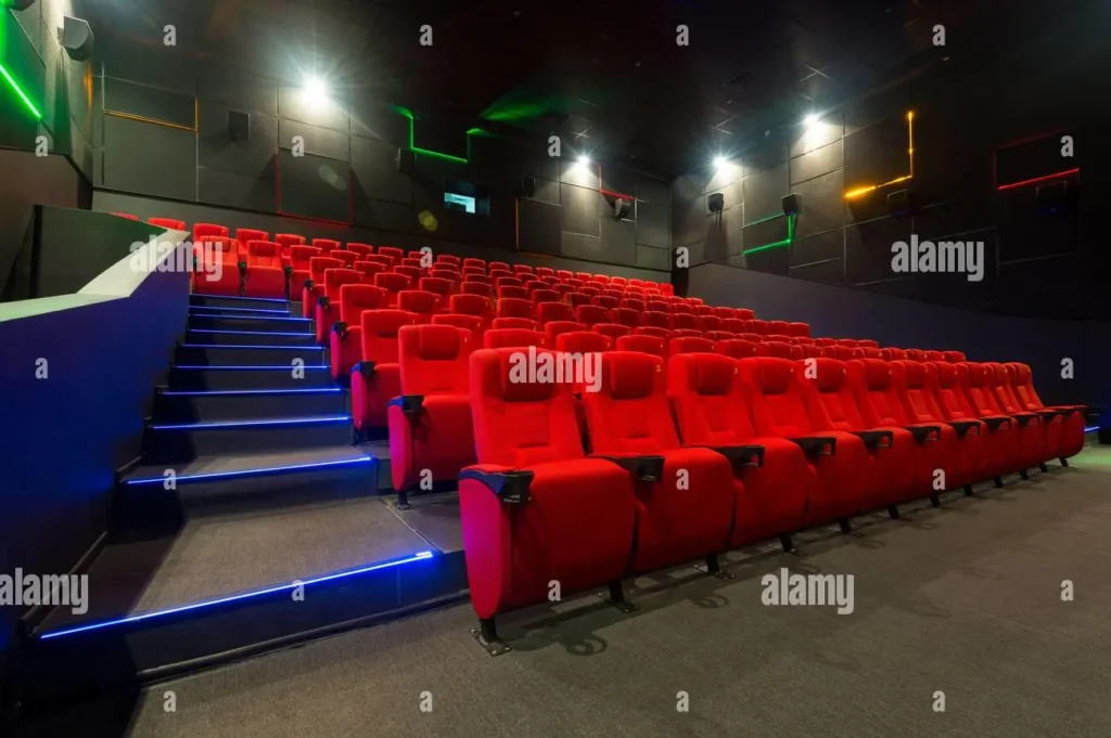 Interior of a modern multiplex cinema with red cushioned seats and ambient lighting illustrating a premium movie-watching experience 