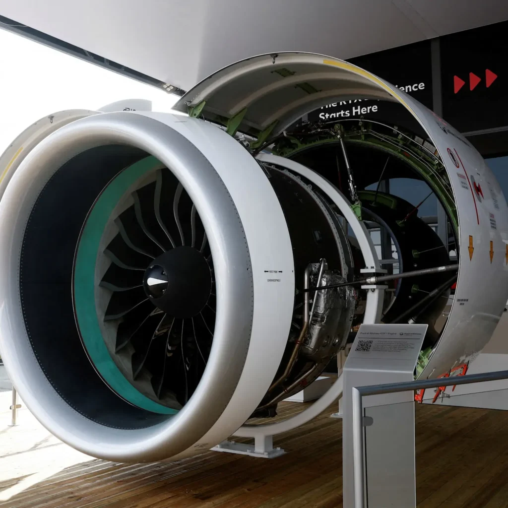 Close-up of a Pratt & Whitney commercial aircraft jet engine with the outer casing opened, showcasing its internal components and fan blades 