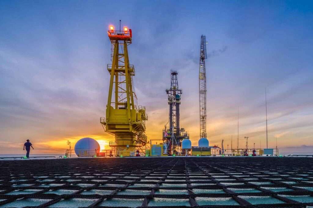 Offshore oil drilling platform during sunset showcasing oilfield service equipment and operations 